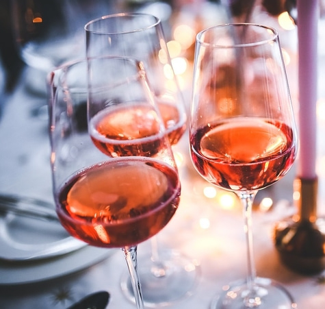 Nahaufnahme von Weingläsern mit Roséwein, festliche Stimmung, Bokeh-Effekt, Tischdekoration