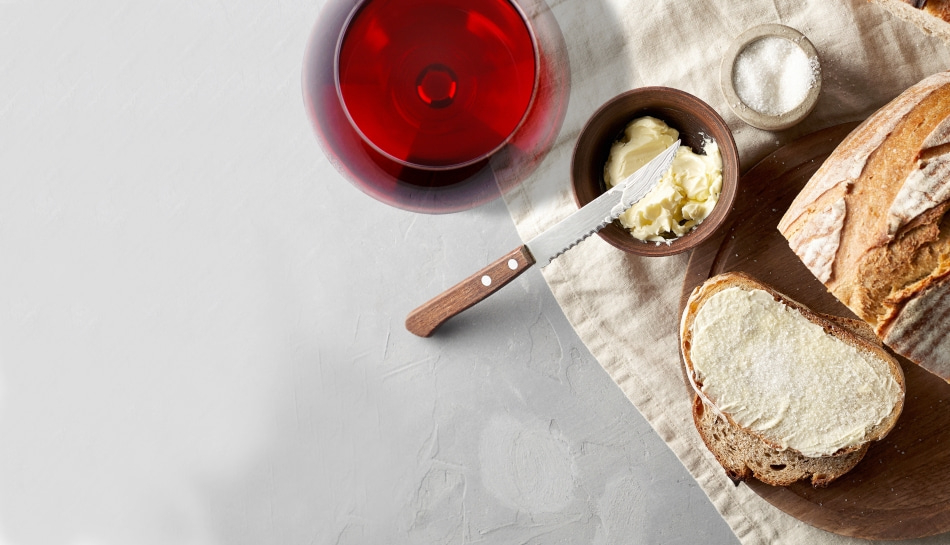 Brot mit Butter, Salz, Wein und Messer auf einem Tisch