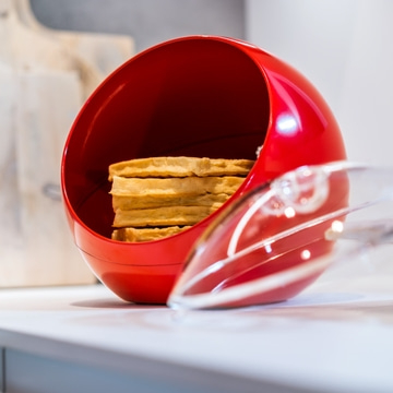Rote Schüssel mit Waffeln und Zange auf weißer Oberfläche