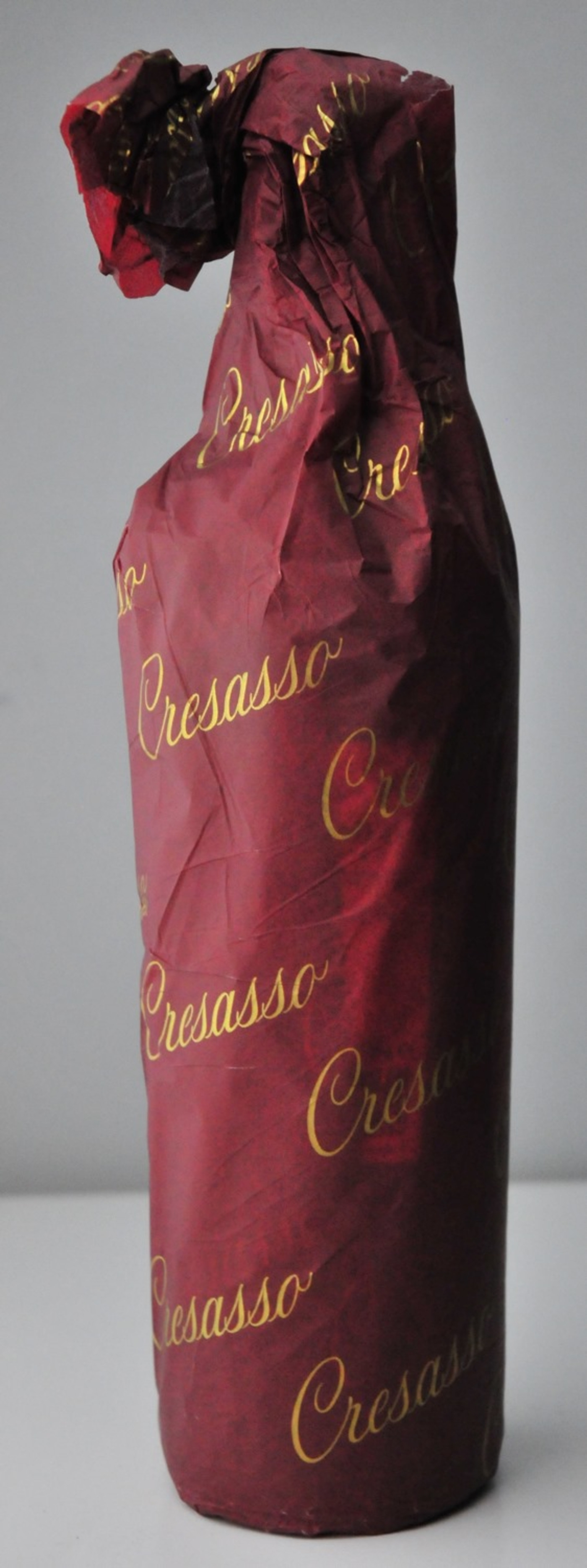 Wein Flasche in rotem Papier mit goldener Schrift, Cresasso