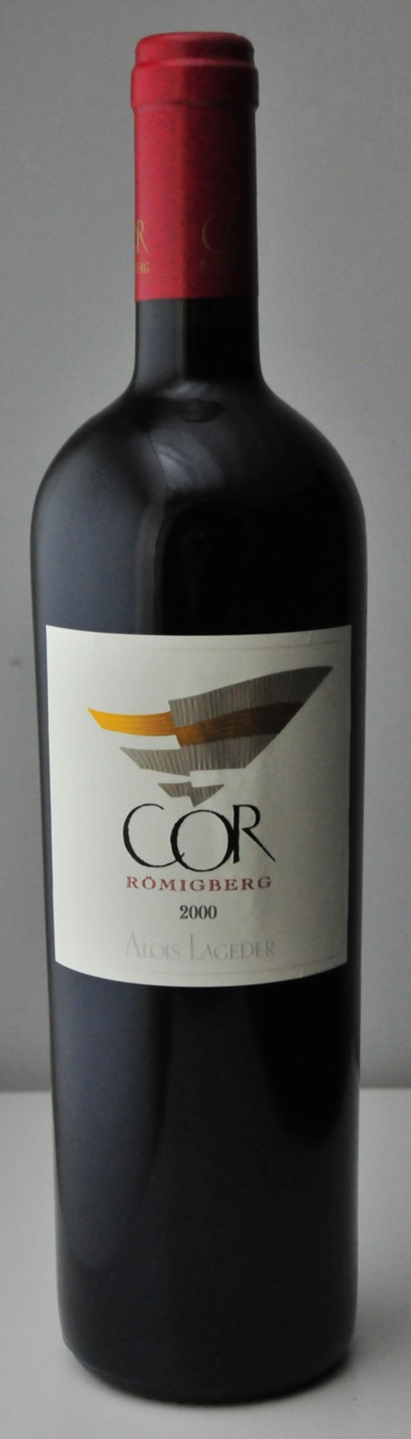 Wein-Flasche mit Etikett 'COR RÖMIGBERG 2000 Alois Lageder' vor grauem Hintergrund