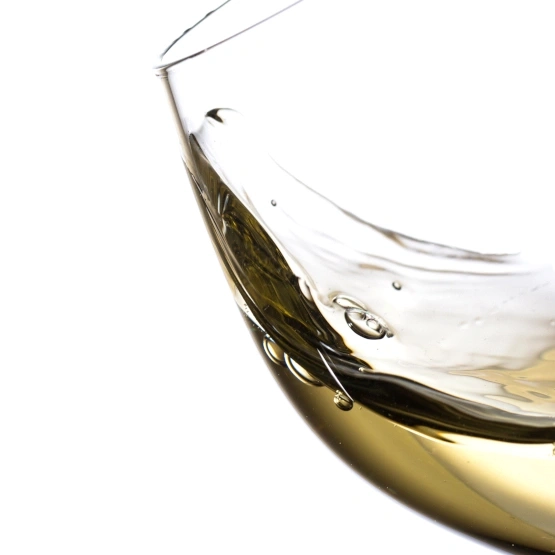 Nahaufnahme eines Weinglases mit Weißwein, der sich im Glas bewegt.